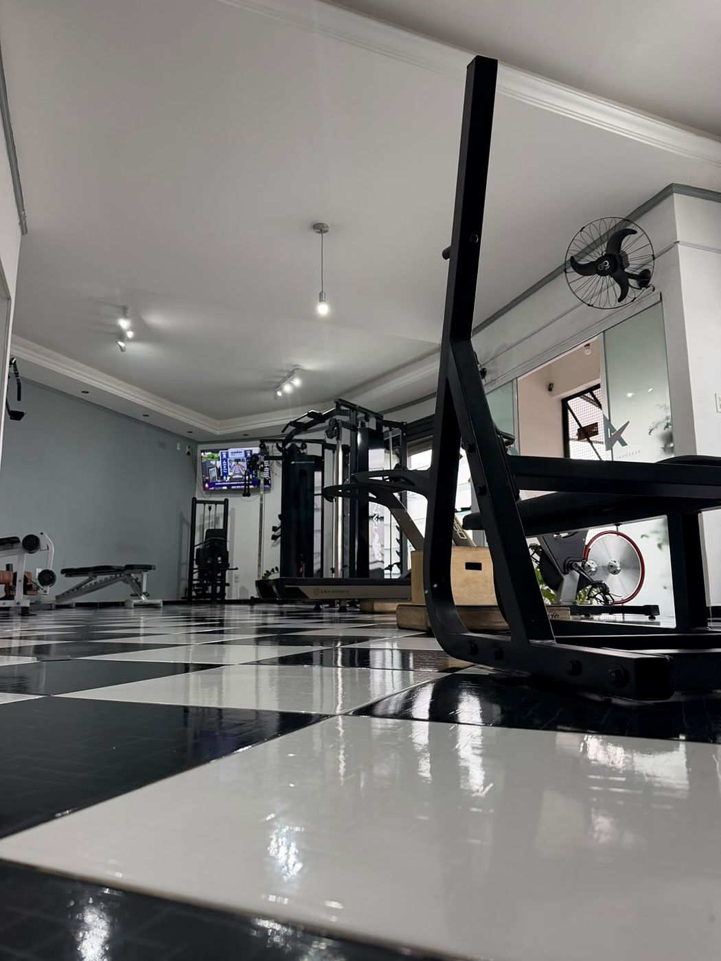Sala de treino do estúdio AC com esteira, estação de musculação e espelhos